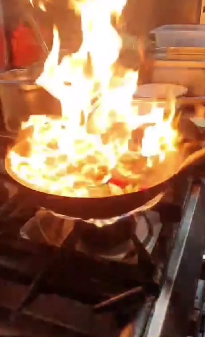 Hohe Flammen schlagen aus dem Wok