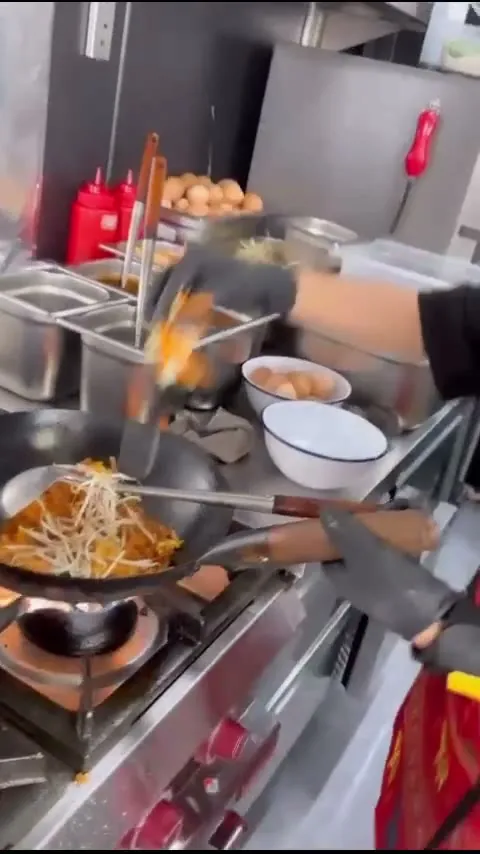 Köchin schwenkt Nudeln im Wok